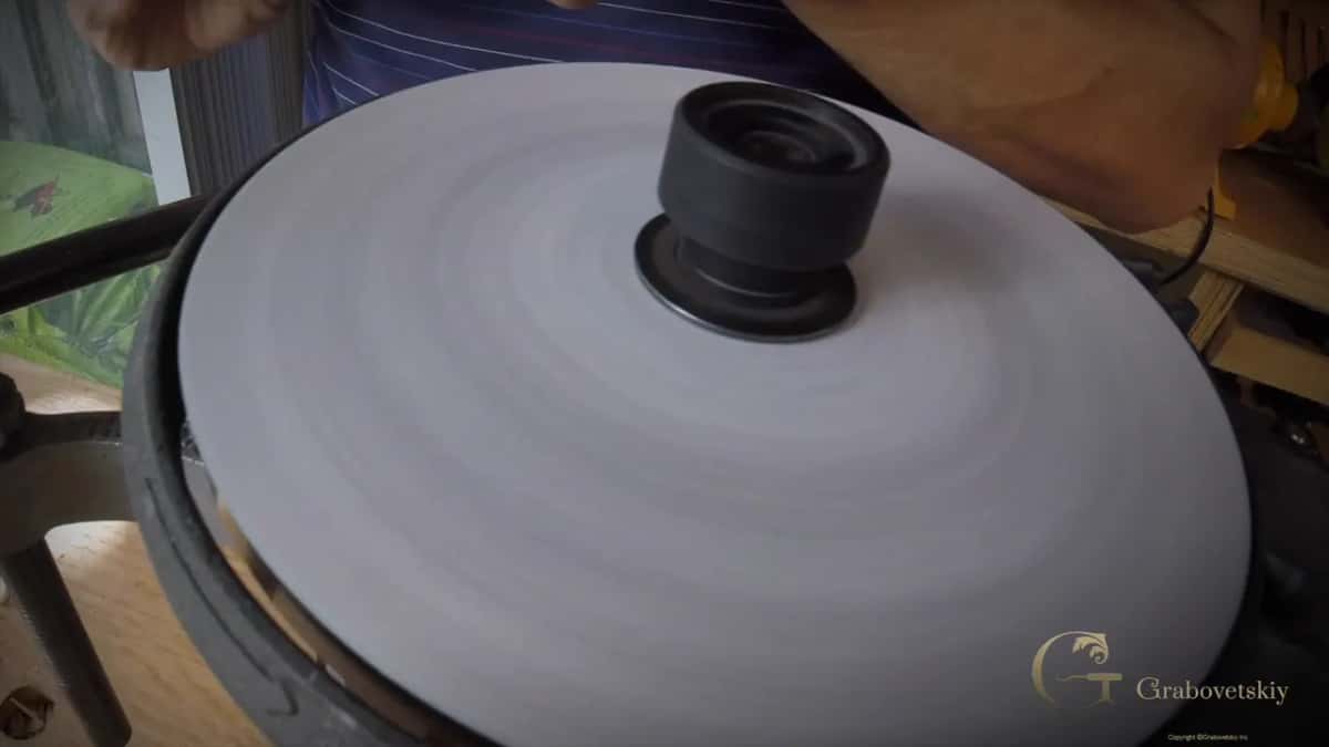 Hands rest above a grey disc as it spins.