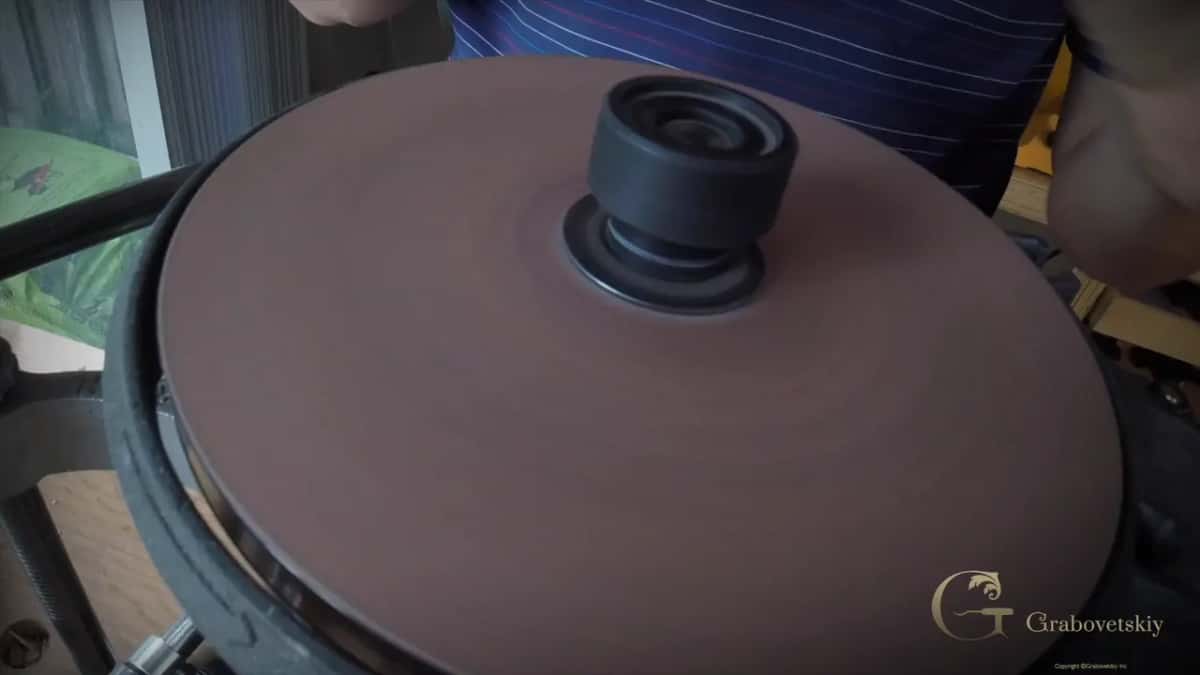 A red-brown disc on the machine, the jig bar reaching in beside it.