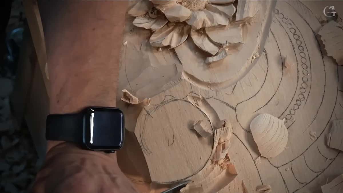 Curled shaving lying on the drawn bands and rows of small circles, with a round shape carved just below it