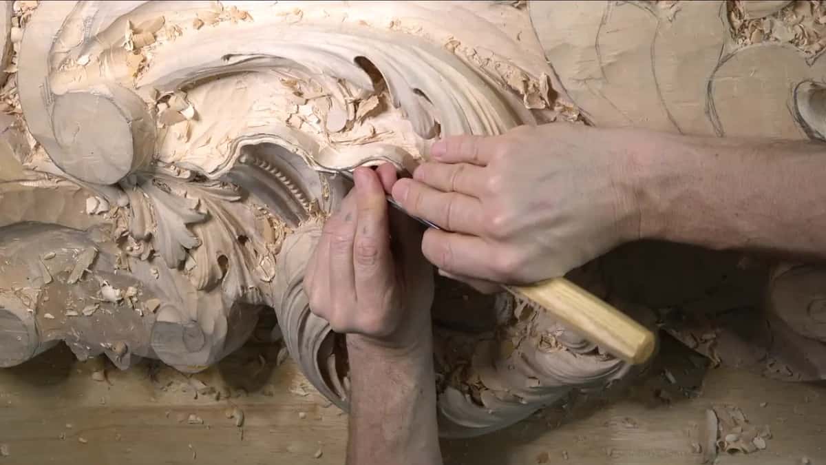 From the far end of the panel, fingers steady a pale handled tool where the rim meets the hollow.