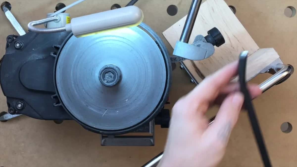 Overhead view of the whole rig, with the Tormek jig raised on a block of wood beside the grinder.