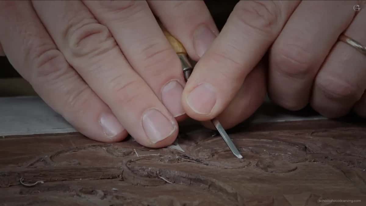 Pale handle in both hands, a hair of steel going in under the carved edge.