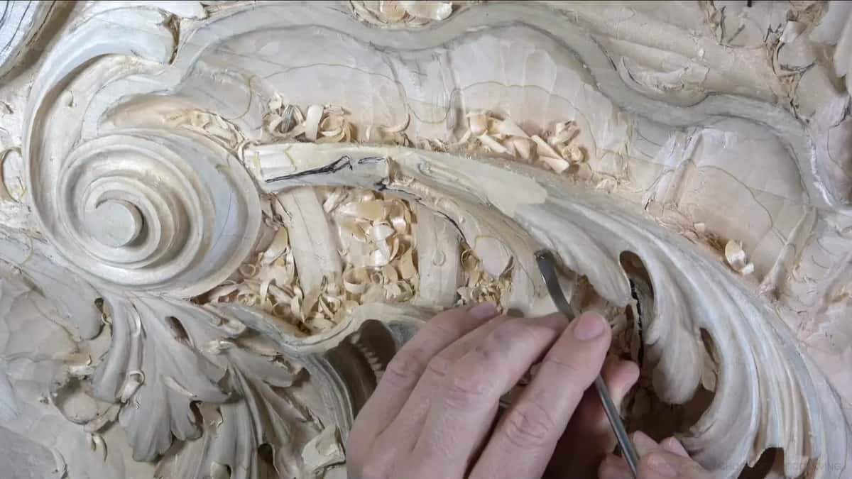 A slim steel tool angles into the leaf's edge, with the hand holding it low.