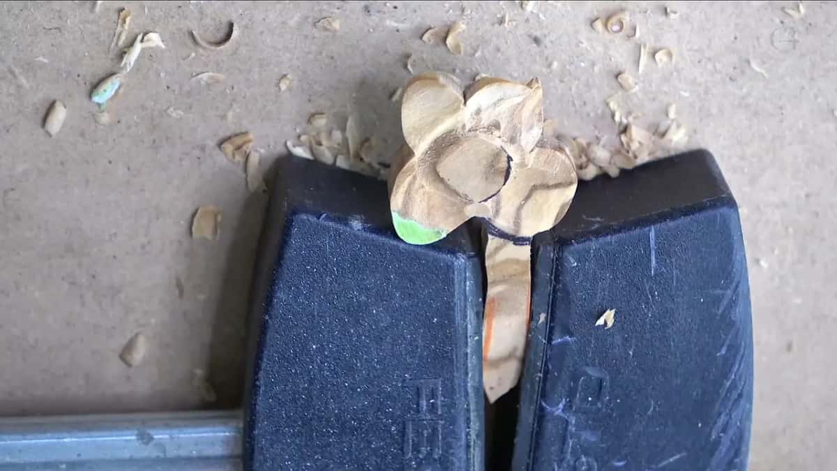 Straight down on the clamped filler, a flat oval with a round center and four petals, chips around it