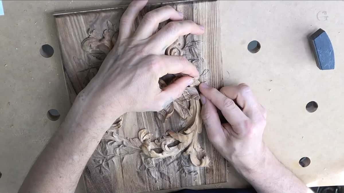Hands setting the small flower onto the carved acanthus lid