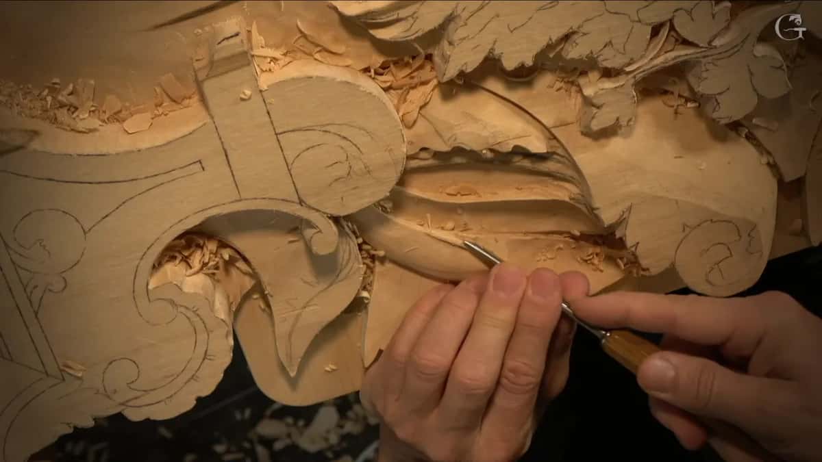 Both hands working the curl where the leaf finishes, pencil lines untouched on the left