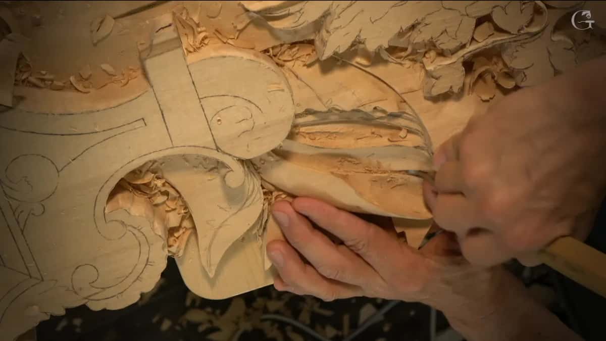 Fingers of the left hand steady the leaf while the right drives a gouge in from the side