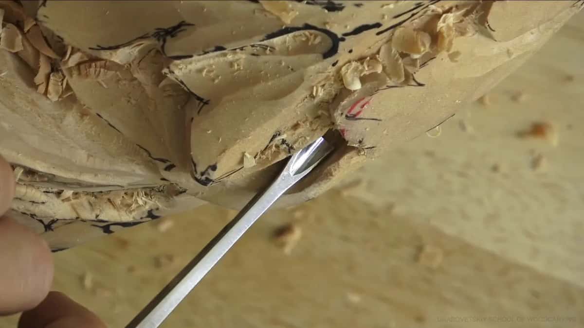 Left hand steadying a small gouge above the hole.