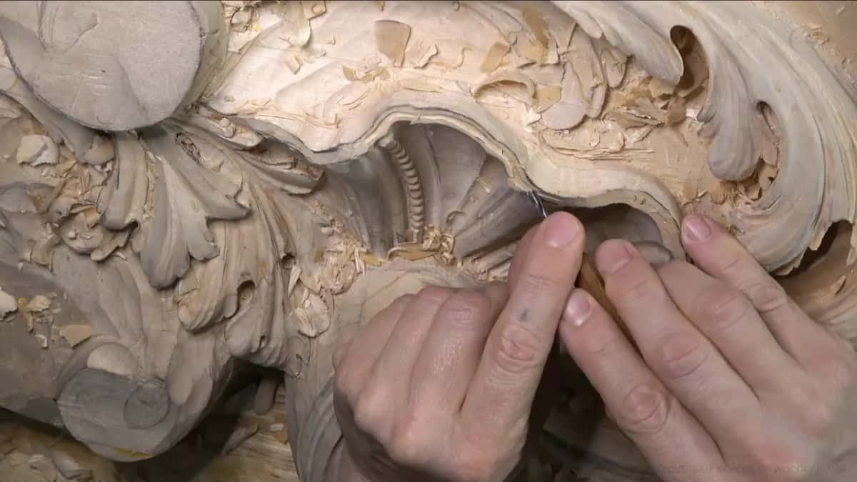 Two hands guide a small gouge around the curve of the rim.