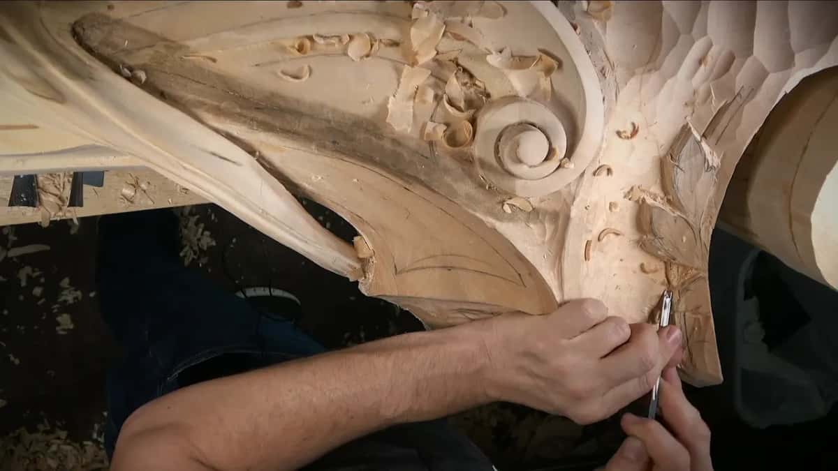 Short gouge working near the scroll, leaf outlines drawn in pencil nearby