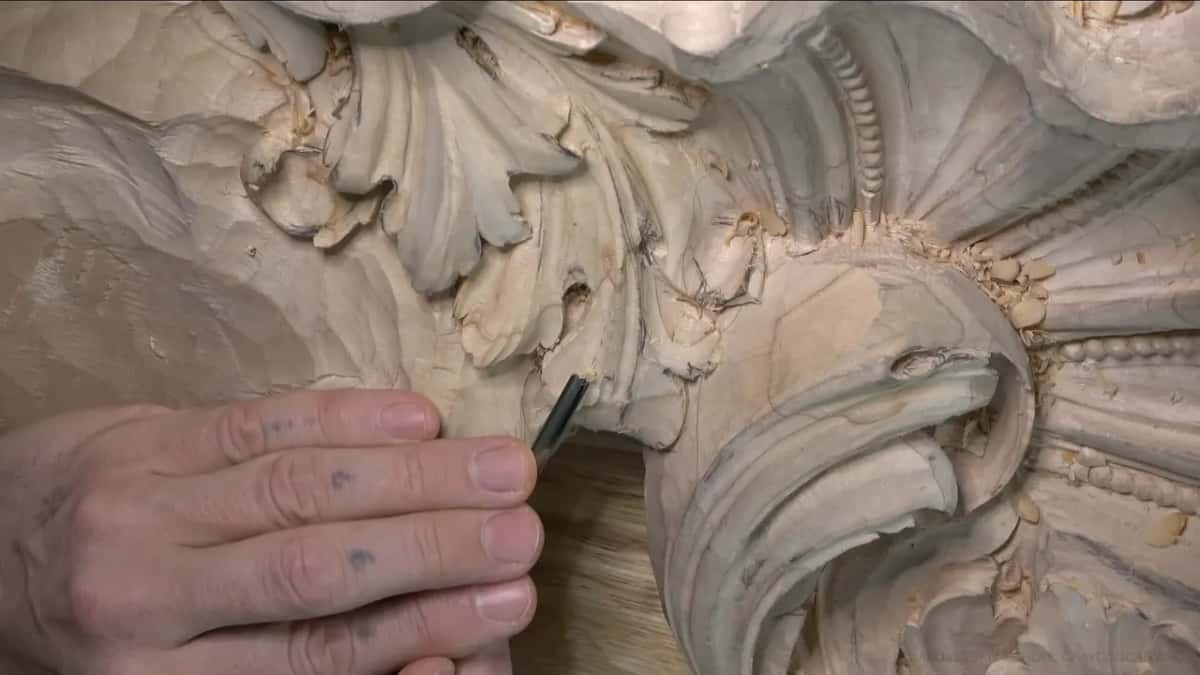 Close view of fingertips on a short gouge, the rolled scroll at right.