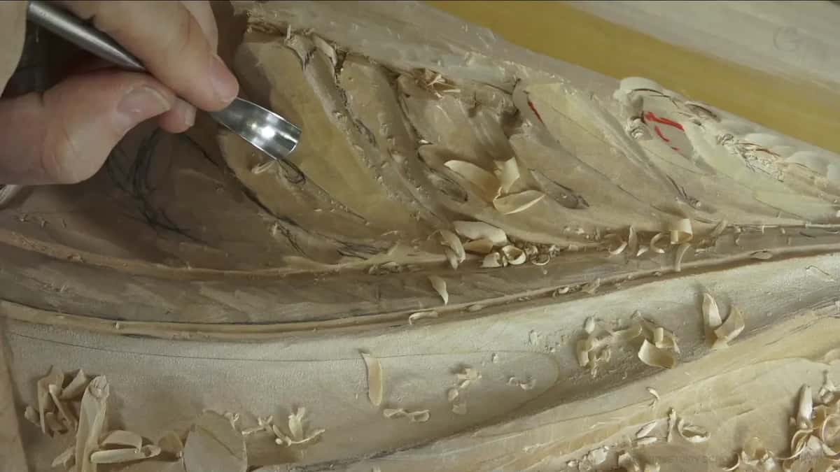 The bent blade of a spoon gouge rests in a long hollow, and one hand shows at the very top.