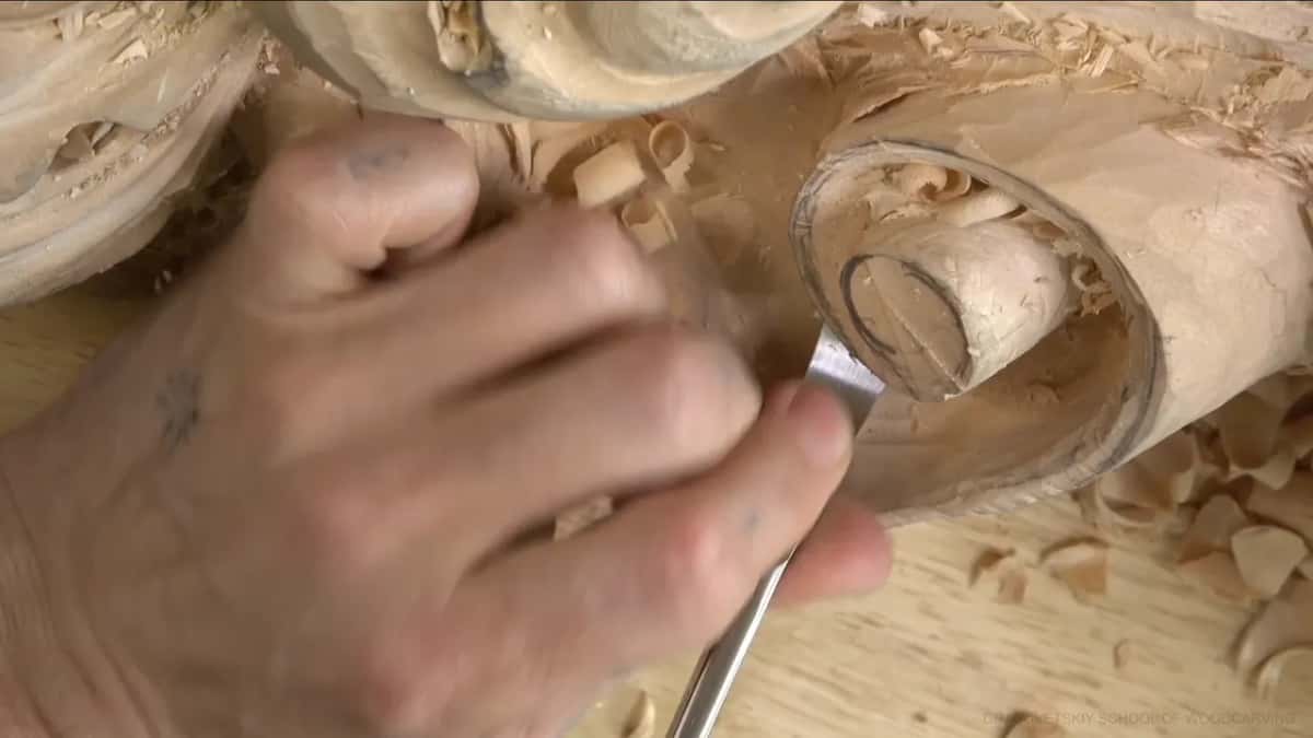 Knuckles curl over a spoon gouge scooping out a round hollow.