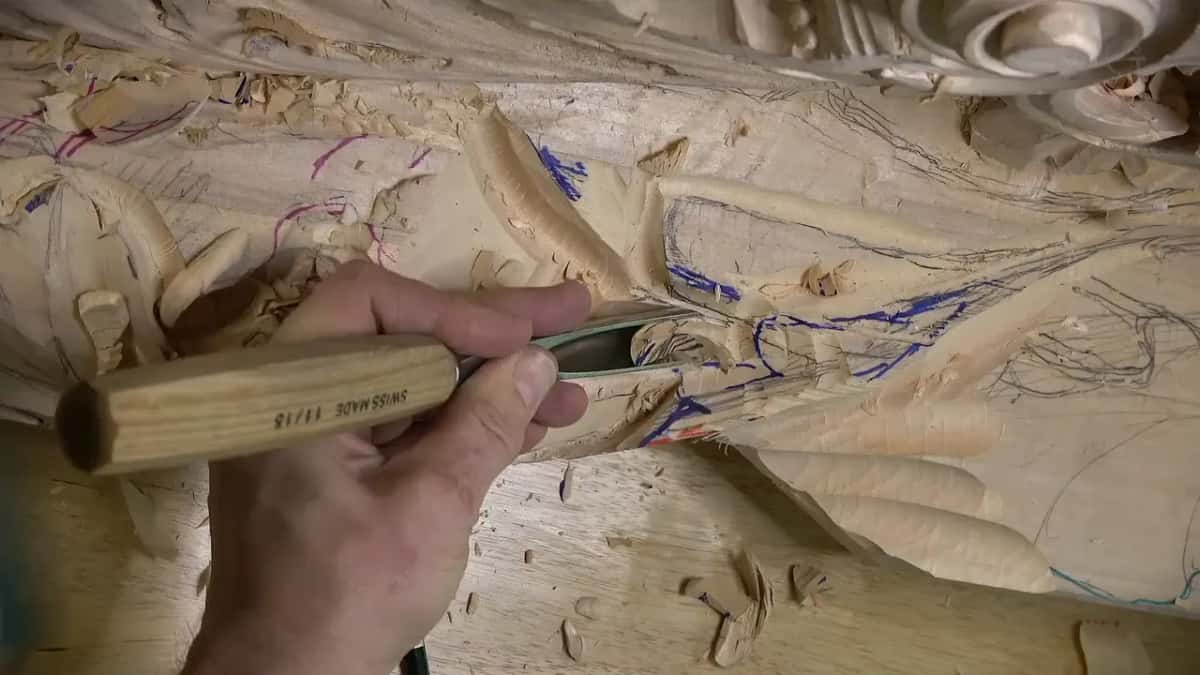 Rough, marked carving under a hand gripping a stamped handle