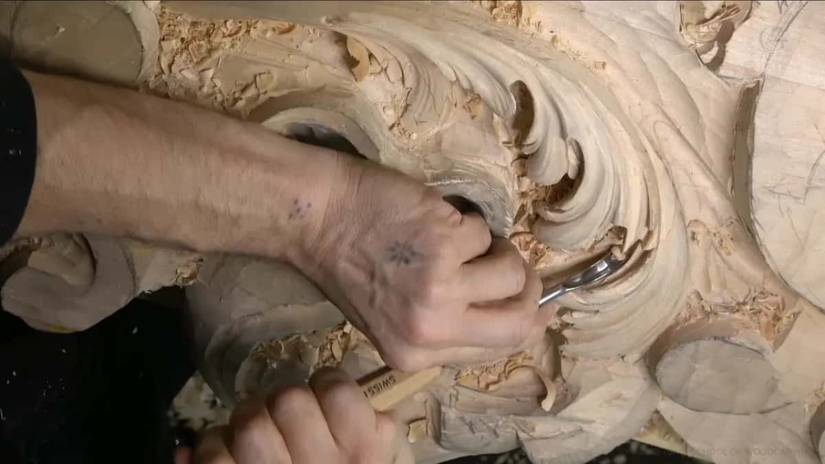 One hand pushes, the other steadies the blade near the shell.