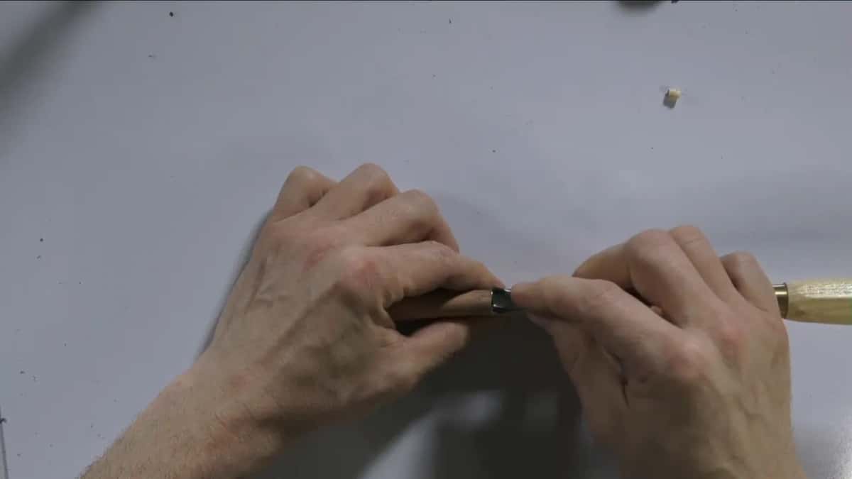 Fingers fold the leather over an edge.
