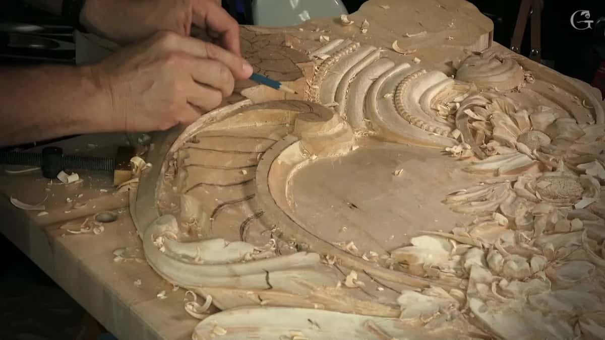 A blue pencil draws on the rounded head beside the ribs and beads, with shavings all over the bench