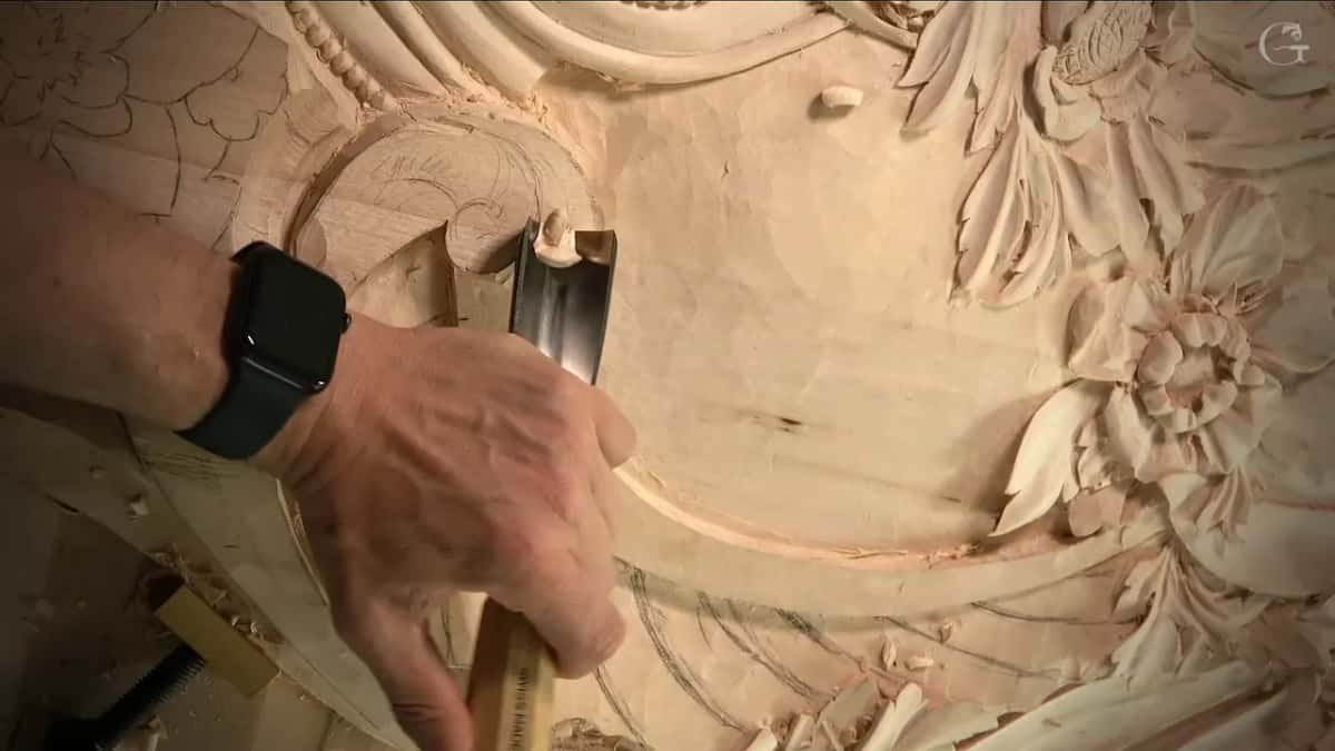 A wide, deep gouge sits upright at the edge of a round head drawn in pencil