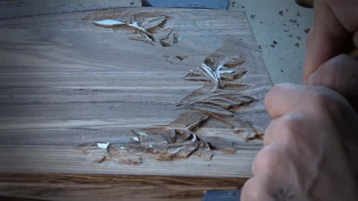 Small carved leaves beside a fist, one of them running underneath and flipping backward.