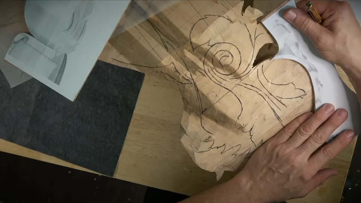 Holding a white plywood template upright against the side of the rough form to check that it matches