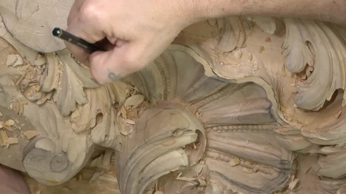 Fingers hold a thin black and silver tool just above the top of the shell's fan.