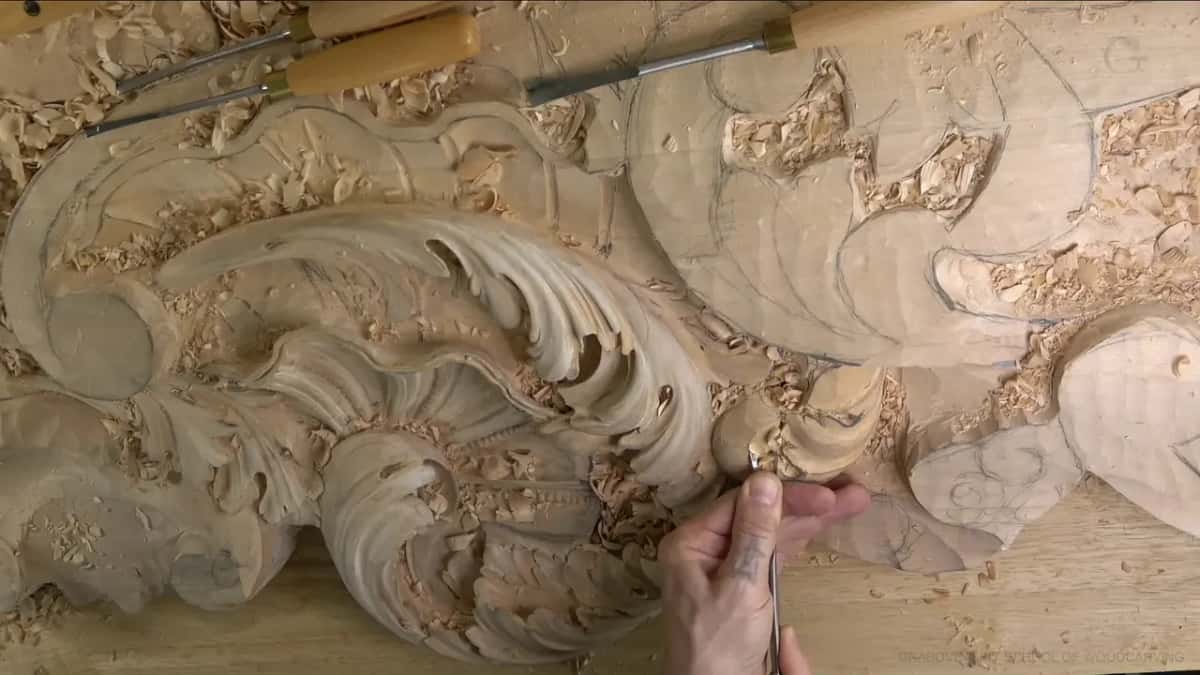 Three gouges rest across the top of the panel while one hand works a small lobe.
