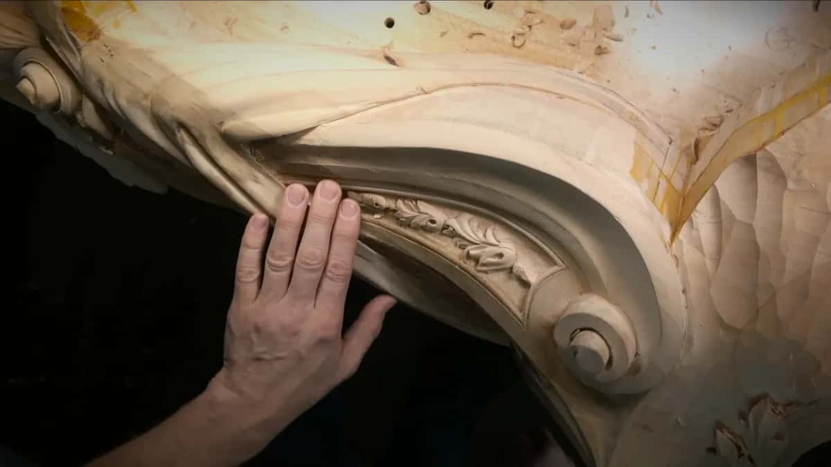 Tiny acanthus leaves carved inside the panel, overhead view with one hand resting beside it