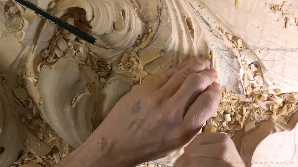 Knuckles press a tool down into the upper lobes, a pencil at the edge.