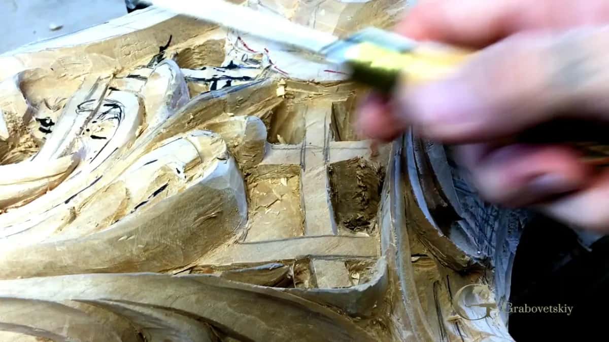 Gouge partway through a cut, the carved surface already deep with shadow, real undercut work under the edge.