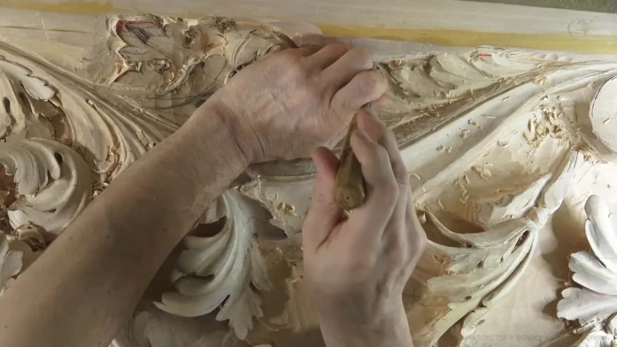 Two hands guide a gouge.
