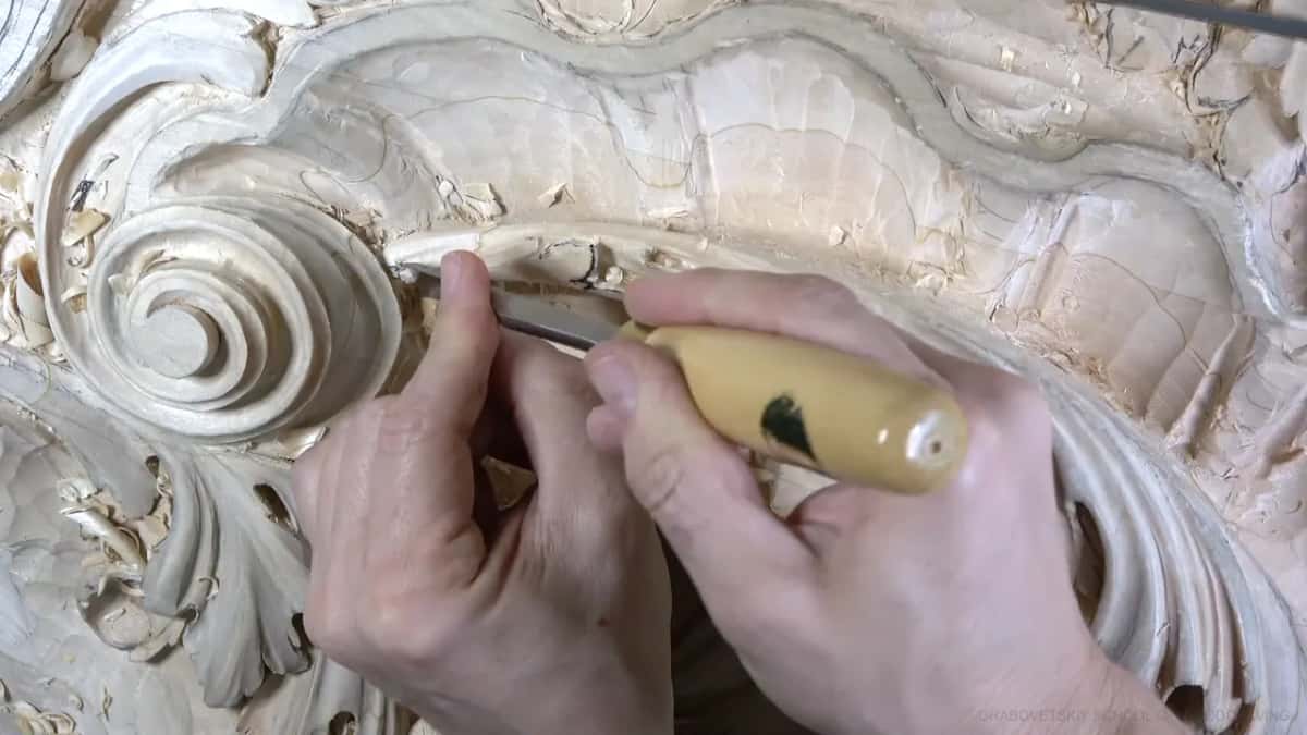 Two hands work the leaf's top edge.