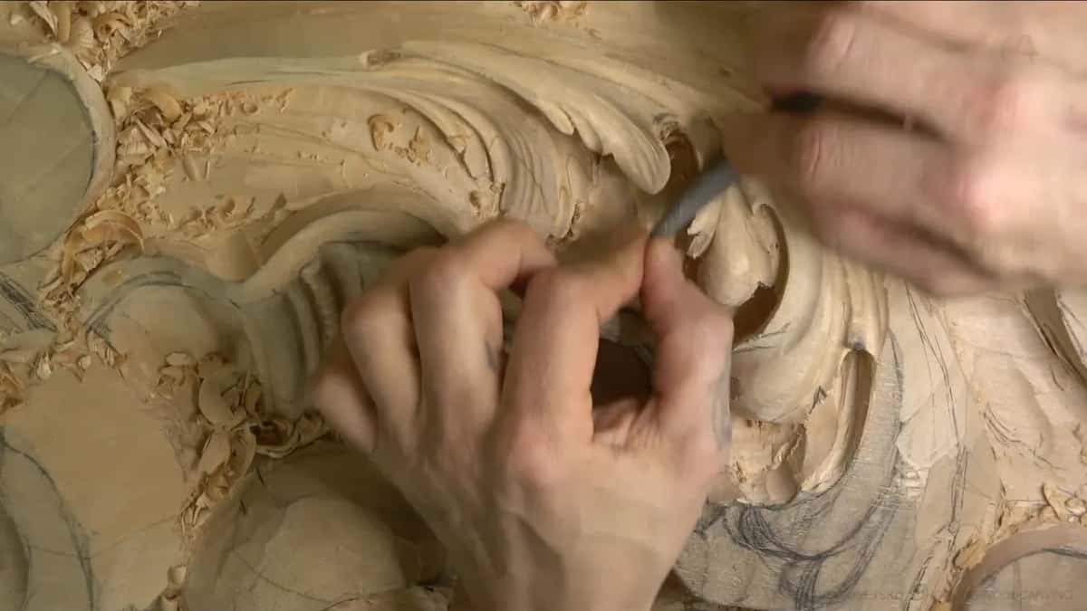 Both hands close together, one steadying the other as a small rasp touches the tip of a leaf.