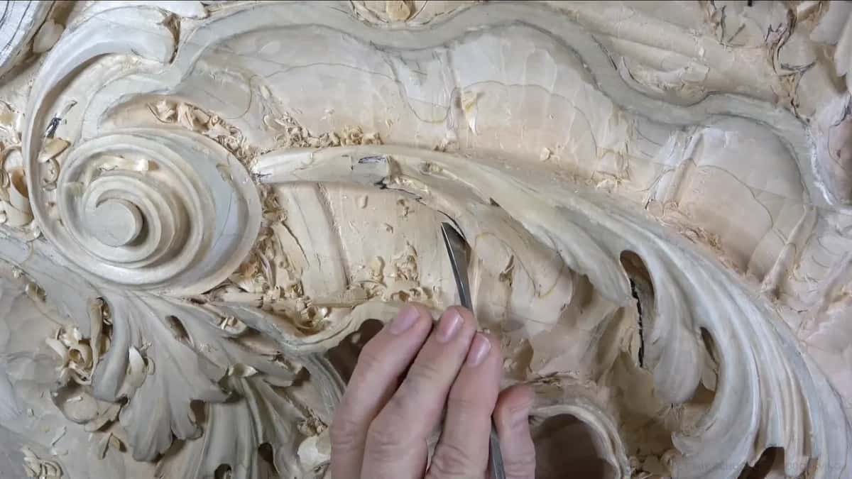 Under the leaf One hand steadying a slim blade under a leaf, with dark openings showing through the carving over to the right