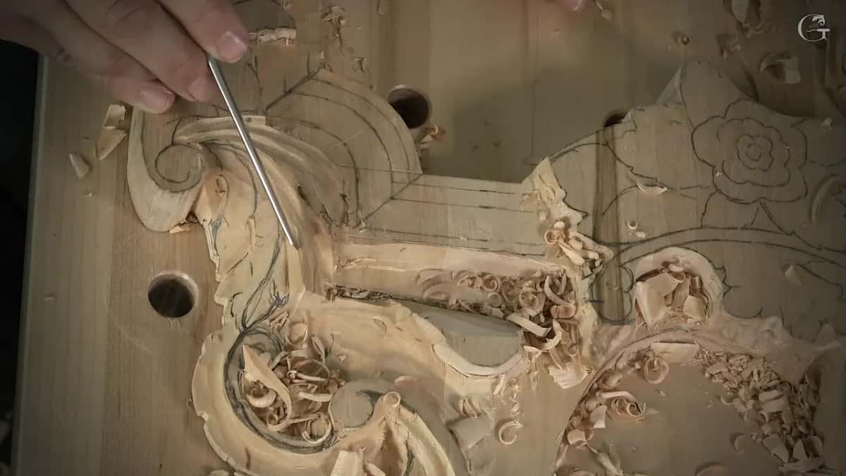 Slim tool beside a volute, tight curls of wood lying where the pipe was shaped