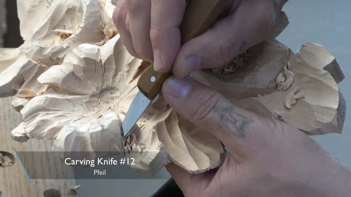 Carving knife with a brass rivet in its handle, worked with both hands into a deep spot