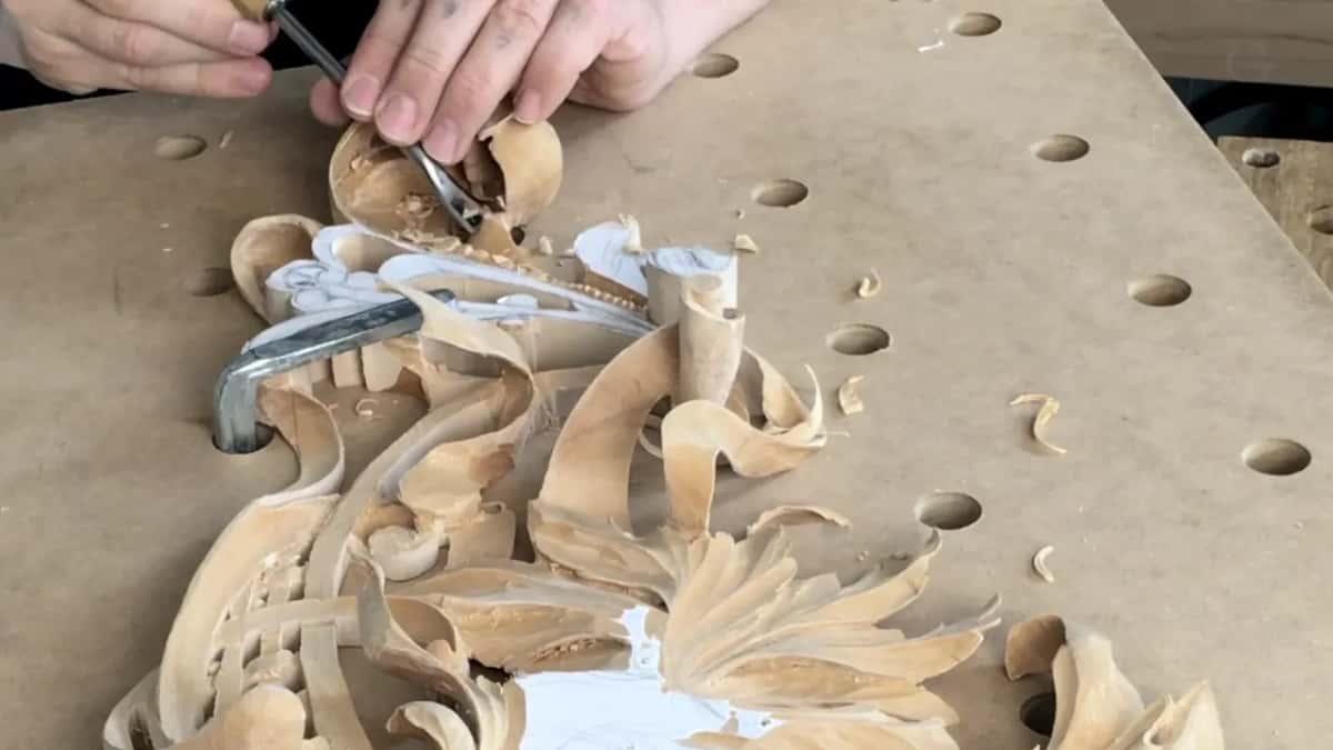 Two hands guide a bent gouge into the top curl