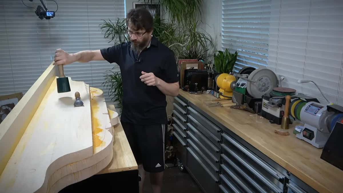 Thirty ounces Black rubber mallet standing upright on the board beside a boxwood gouge