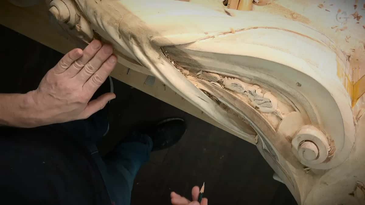 Carved scroll block seen from above, one hand resting on it