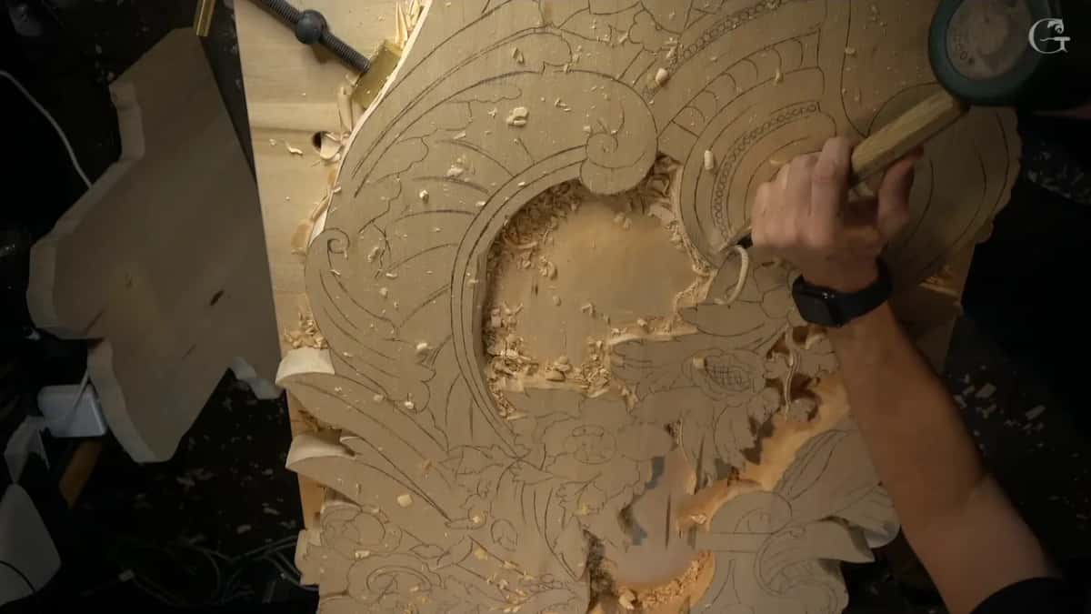 Overhead view of the whole panel, one hand working a gouge along the drawn fan at the top right.