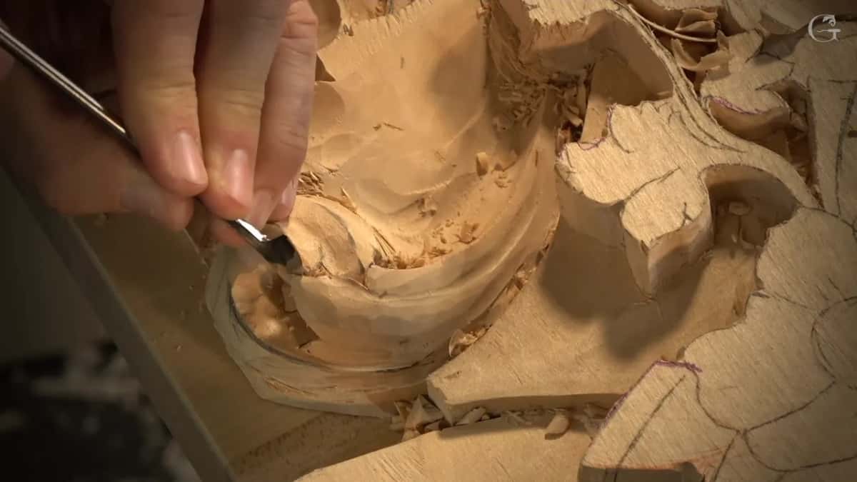 Small gouge scooping inside the hollow next to the lobed leaf, shavings still sitting in it.