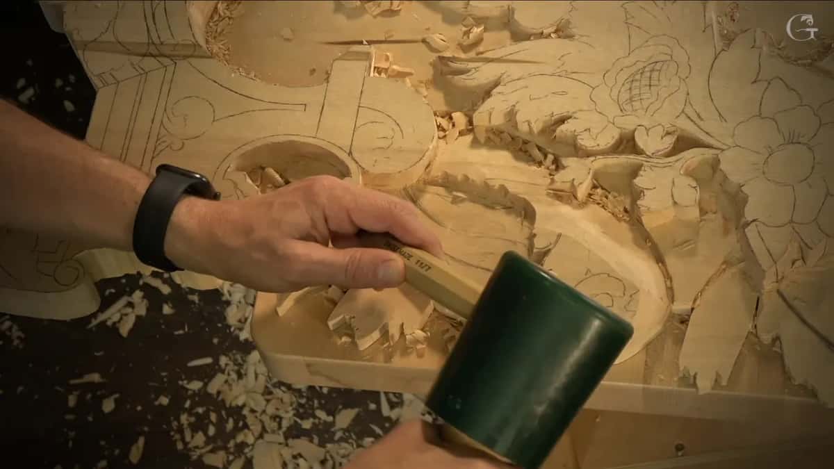 Green mallet behind a gouge, working on the line under a pencil flower whose middle is crosshatched.