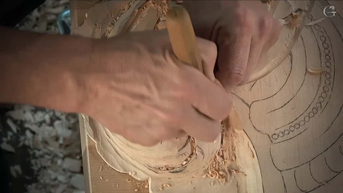 Both hands on one pale handle, the blade in the hollow of the scroll