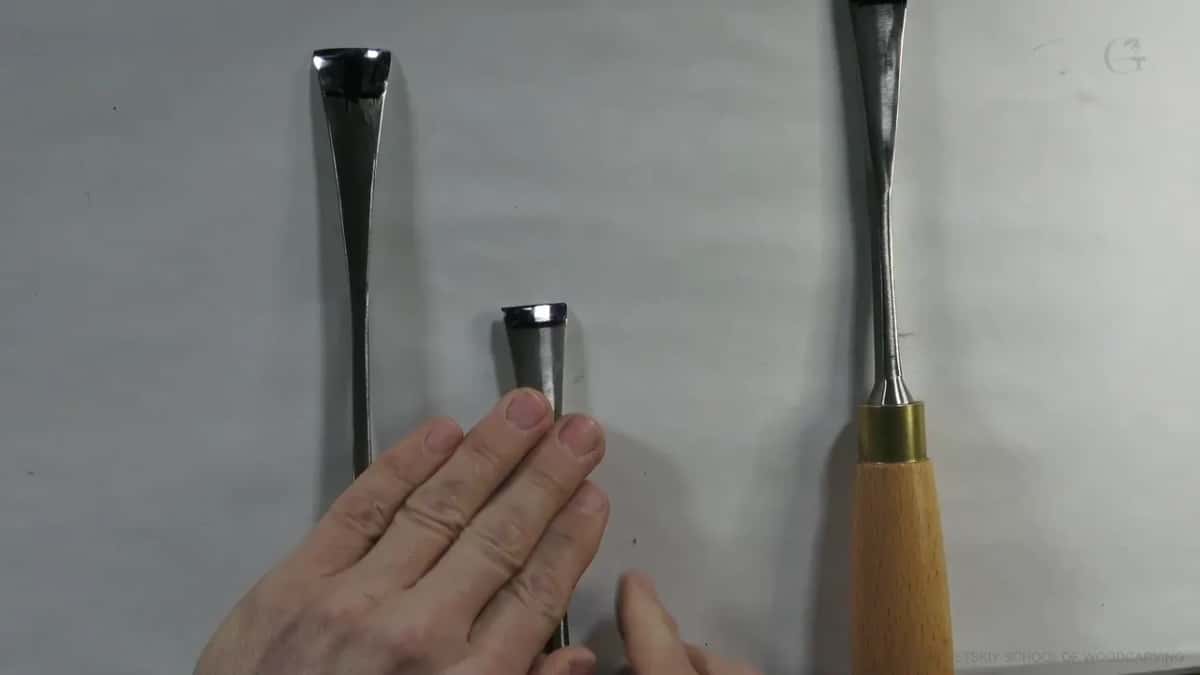 Two blades, a finger resting where the steel widens out toward the ferrule and the handle begins.