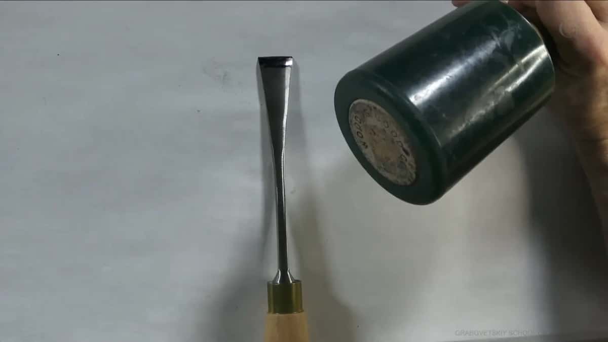 Heavy green mallet lying beside a gouge.