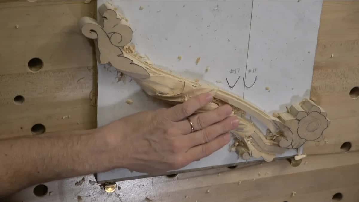 Both hands off the work, looking.