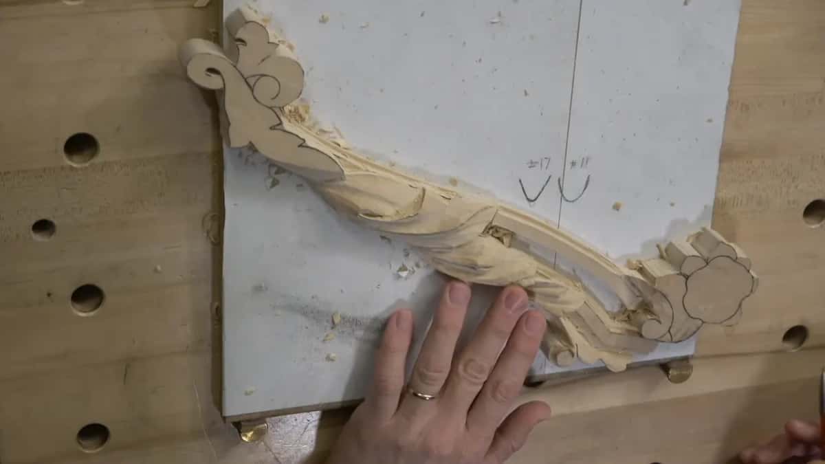 The carved swag from above with a hand resting on it, several spots still unshaped.