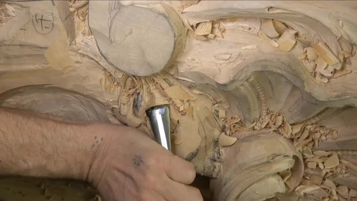 Forearm and fist behind a wide gouge held straight down.