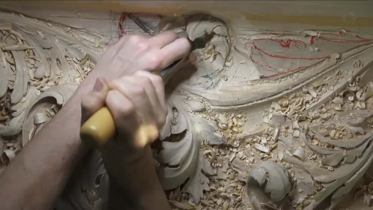 Both fists close around a thick yellow handle, a wide gouge down in fresh chips.