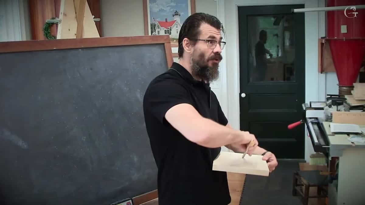 Alexander holds a pale board at chest height with the tool high