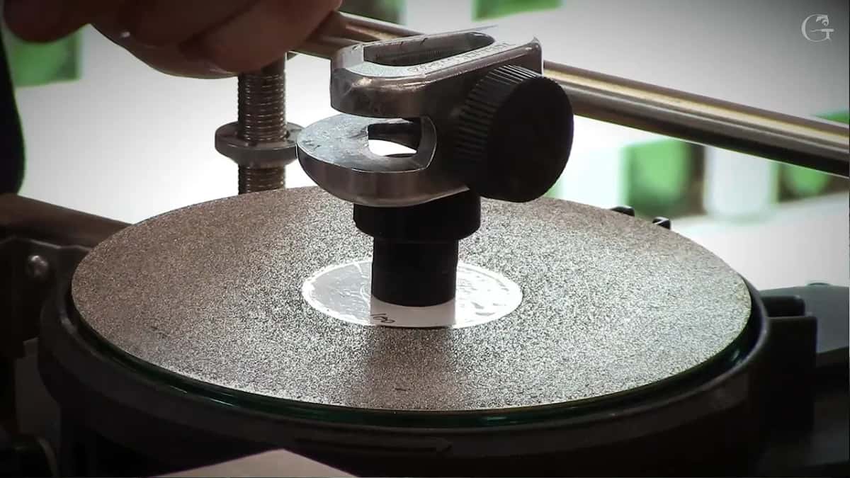 Tormek jig with its big knurled knob stands over a coarse silver diamond disc, the guide bar behind it